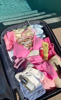 an open suitcase filled with clothes next to a swimming pool