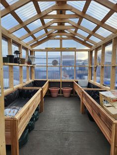 the inside of a wooden greenhouse with potted plants and other things in pots on the floor