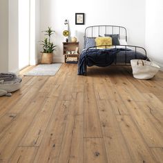 a bedroom with white walls and wood floors, including a bed in the middle of the room