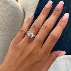 a woman's hand with a diamond ring on her left hand and the other hand holding an engagement ring