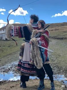 two people dressed in native american clothing with bows and arrows