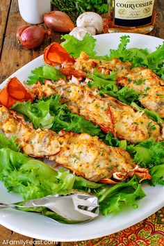 lobsters and lettuce on a white plate next to garlic, onions, and parsley