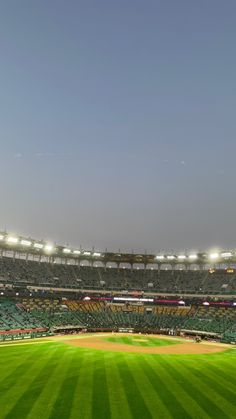 an empty baseball stadium filled with lots of green grass and lights on the sidelines