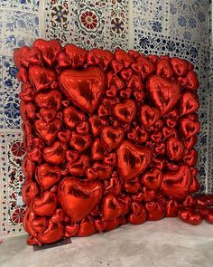 a large red heart sculpture sitting on top of a white floor next to a wall