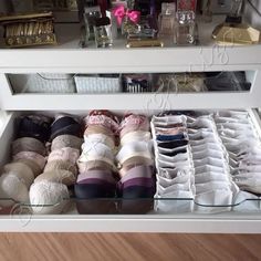 an open drawer with many pairs of shoes on it and other items in the bottom shelf