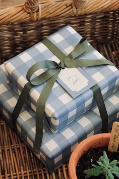 a stack of wrapped presents sitting next to a potted plant and wicker basket