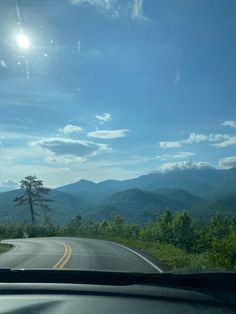 the sun shines brightly over mountains as seen from inside a car