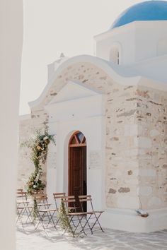 an old church with chairs and flowers on the outside