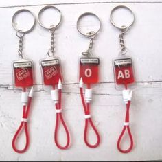 four red and white keychains with the letters ab on them are hanging from hooks