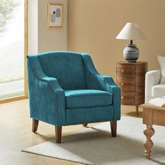 a blue chair sitting in a living room next to a lamp