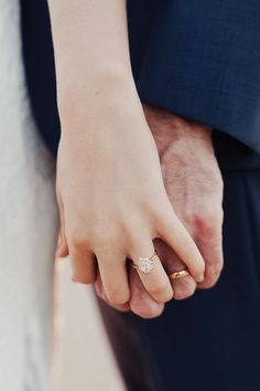 a close up of a person holding the hand of another person wearing a wedding ring