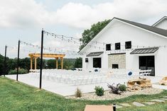 an outdoor wedding venue with white chairs and string lights on the side of the building