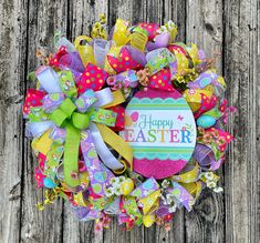 a colorful easter wreath with the words happy easter written on it, sitting on a wooden surface