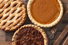 three pies on a wooden table with spoons and utensils