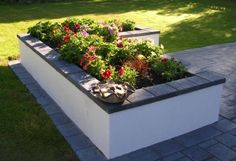 a planter filled with lots of flowers sitting on top of a cement block wall