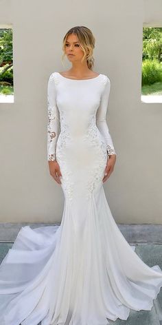 a woman wearing a white wedding dress with long sleeves