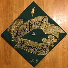 a green and gold graduation cap with the words, school manager on it's side