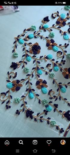 an applique is displayed on a table with blue and green beads in it