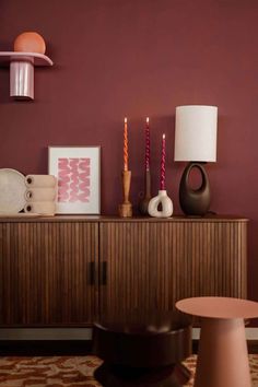 a living room with purple walls and wooden furniture in the corner, candles on top of an entertainment center