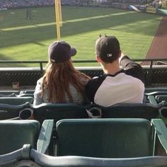 two people are sitting in the stands at a baseball game looking out into the field