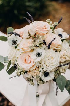 a bridal bouquet with white flowers and greenery on the back of a chair