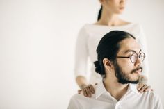 a man with glasses standing next to a woman in a white shirt and black hair