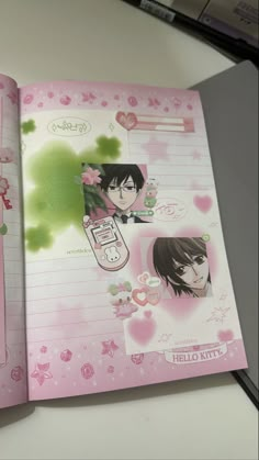 an open pink notebook with pictures of people on the pages and hearts around it, sitting on a table