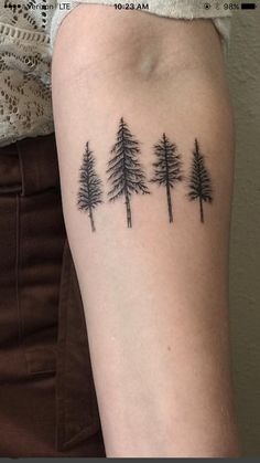 a woman's arm with three pine trees on it