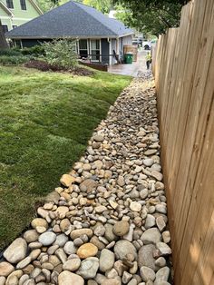 rocks are lined up along the side of a wooden fence in front of a house