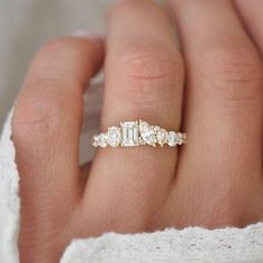 a woman's hand with a diamond ring on top of her finger and an engagement band in the middle