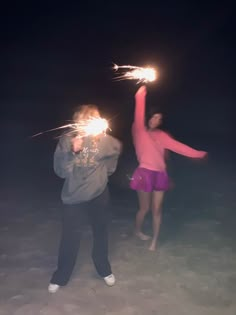 two people holding sparklers in the dark