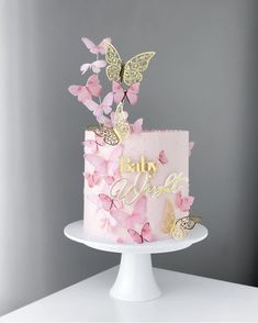 a pink and gold cake with butterflies on top that says baby we're one