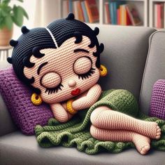 a knitted doll laying on top of a couch next to a stuffed animal toy