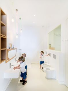 two children playing in a bathroom with toilet and sink