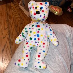 a white teddy bear with multicolored dots on it