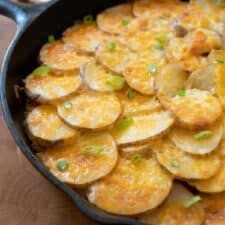 a skillet filled with potatoes on top of a wooden table