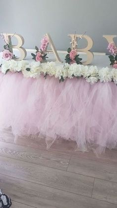 the table is decorated with pink and white tulle skirted flowers, gold letters that spell out baby