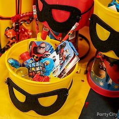 a yellow bucket filled with lots of toys and other items sitting on top of a table