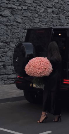 a woman is getting out of her car with a large bouquet of flowers