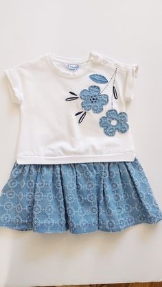 a white shirt with blue flowers on it and a light blue skirt for the bottom