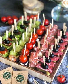 an assortment of appetizers are arranged on a tray with toothpicks and tomatoes