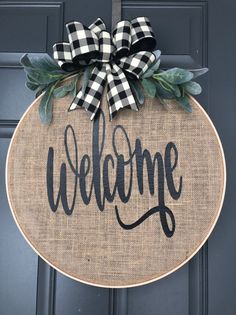 a welcome sign hanging on the front door with a black and white checkered bow