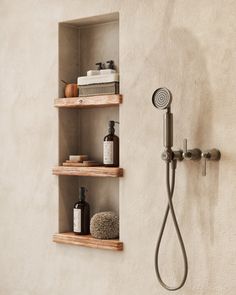 a shower head and shelves with soap, lotion, shampoo and other items