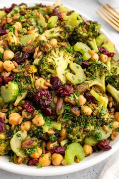 a white bowl filled with broccoli, beans and cranberry salad on top of a table