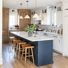 a kitchen island with stools in front of it and lights hanging from the ceiling