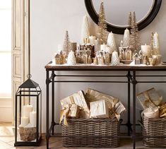 a table topped with baskets filled with christmas trees and candles next to a mirror on the wall