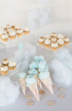 some cupcakes are sitting on top of small cones and stars in the clouds