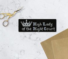 a pair of scissors sitting on top of a table next to a sign that says high lady of the night court