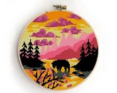 a cross - stitch pattern in the shape of a sunset with trees and clouds on it