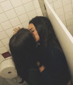 two women are kissing in a bathroom stall